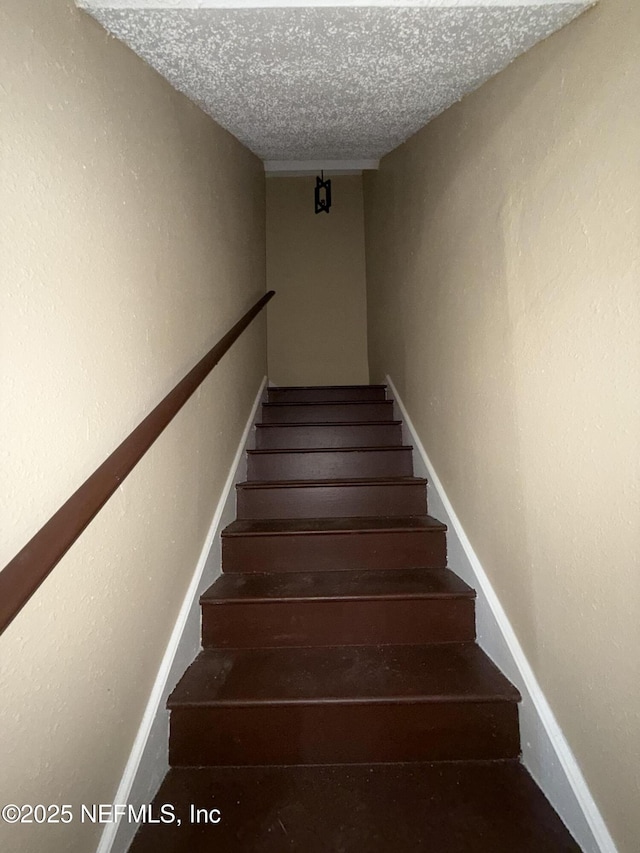 stairway with a textured ceiling and baseboards