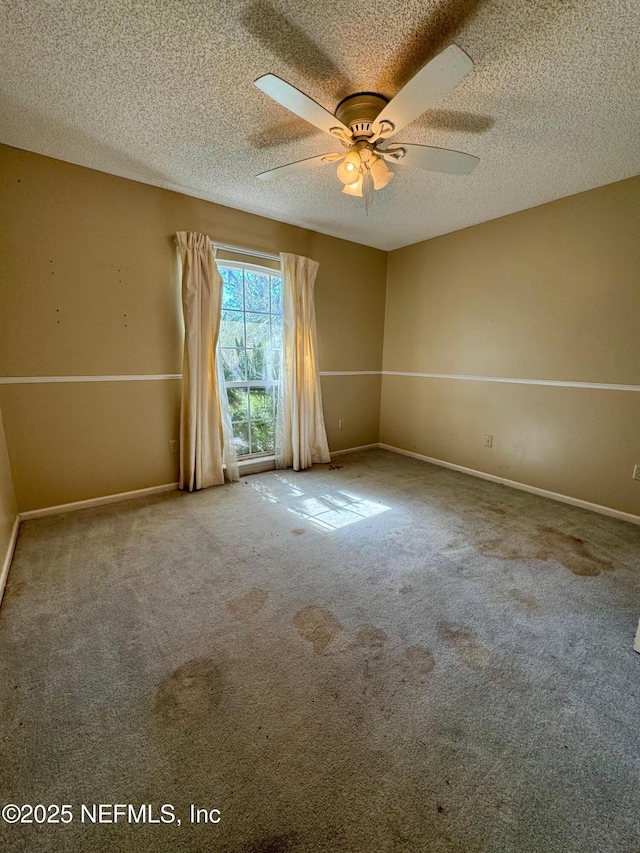 carpeted spare room featuring a ceiling fan, baseboards, and a textured ceiling