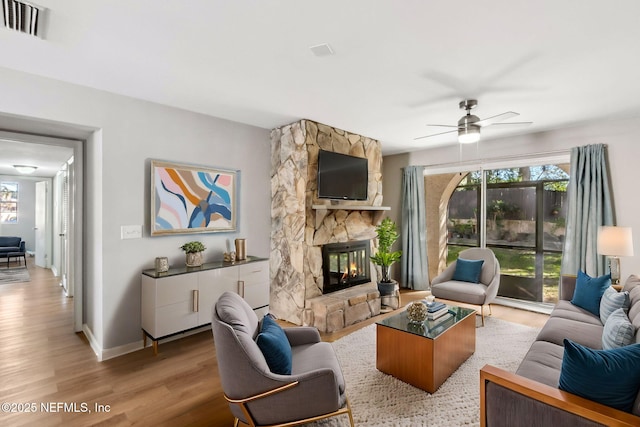 living room with light wood-type flooring, visible vents, a healthy amount of sunlight, and a fireplace