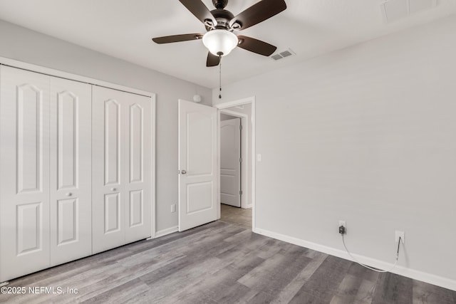 unfurnished bedroom featuring visible vents, a closet, and wood finished floors