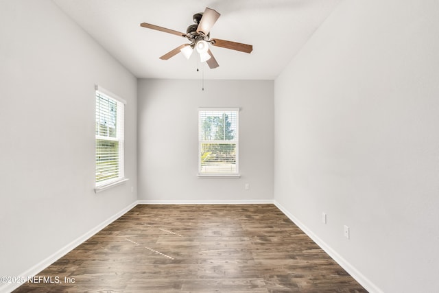 spare room with dark wood-style floors, a healthy amount of sunlight, baseboards, and a ceiling fan