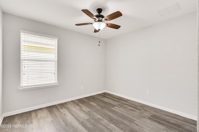 spare room with a ceiling fan, visible vents, baseboards, and wood finished floors