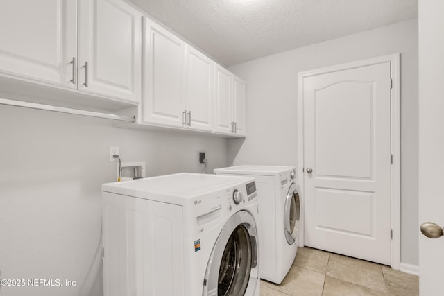 washroom featuring cabinet space, separate washer and dryer, a textured ceiling, and light tile patterned flooring