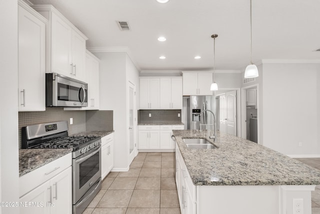 kitchen with stainless steel appliances, a sink, visible vents, backsplash, and an island with sink