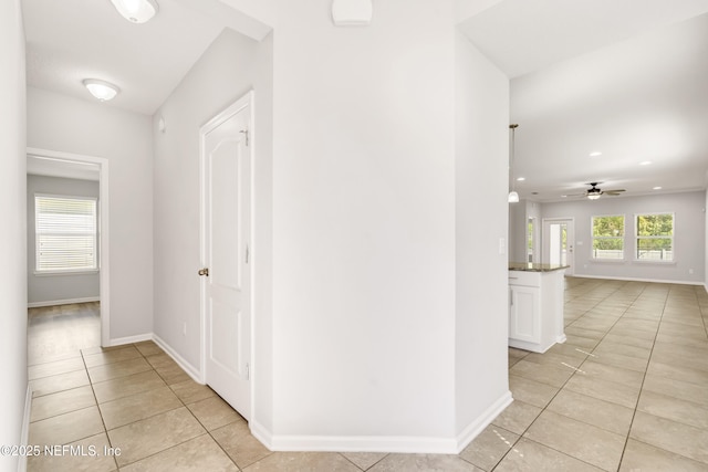 hallway with light tile patterned flooring and baseboards