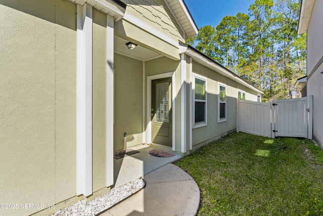 view of home's exterior with a lawn, fence, a gate, and stucco siding