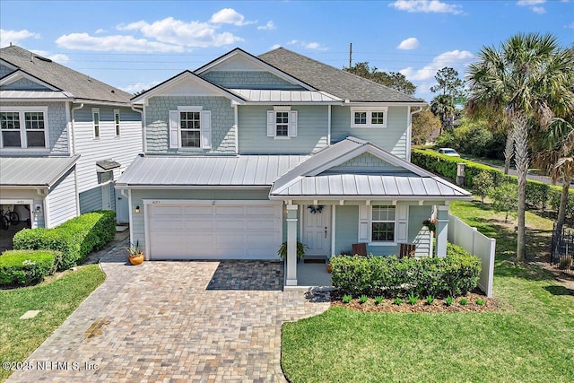 view of front of home with a porch, a front yard, decorative driveway, a garage, and a standing seam roof