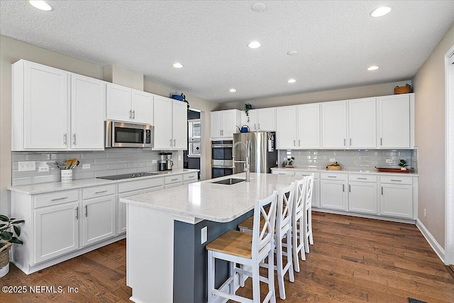 kitchen featuring white cabinetry, a kitchen island with sink, dark wood-style flooring, and stainless steel appliances