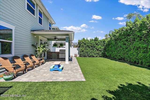 view of yard featuring fence, exterior kitchen, a ceiling fan, and a patio area