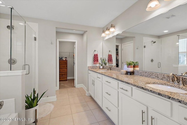 full bath featuring visible vents, a sink, a shower stall, double vanity, and a spacious closet