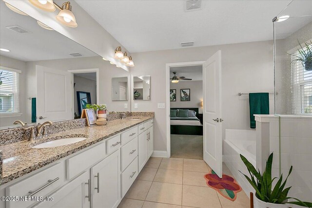 ensuite bathroom featuring a sink, visible vents, double vanity, and tile patterned floors