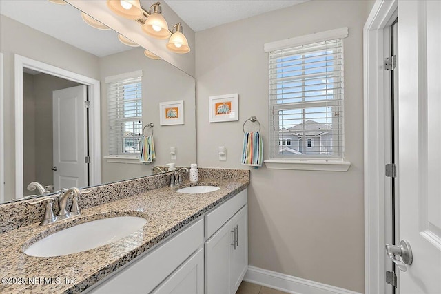 bathroom featuring double vanity, baseboards, and a sink