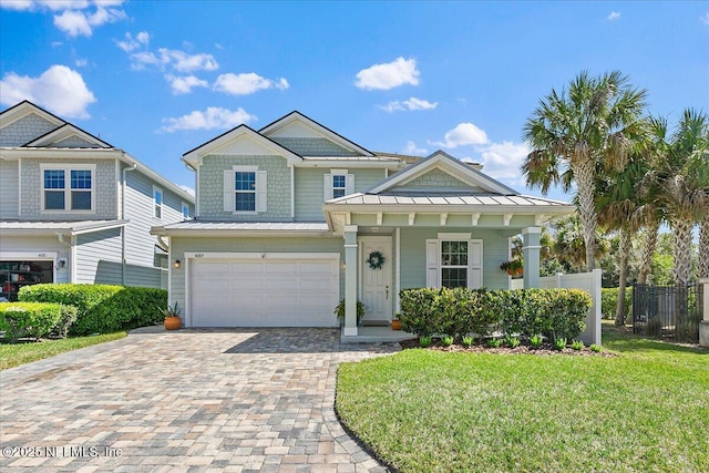 view of front of property with a front lawn, a standing seam roof, decorative driveway, fence, and a garage