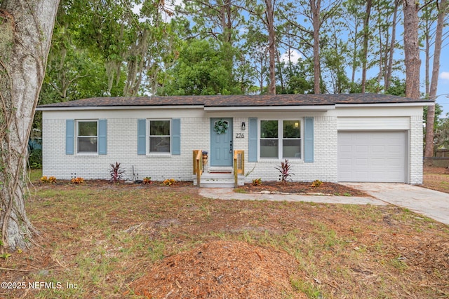 single story home with driveway, brick siding, and an attached garage