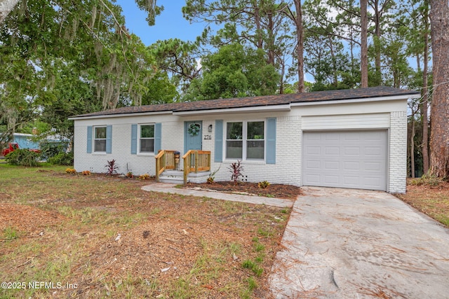 single story home with concrete driveway, brick siding, and a garage