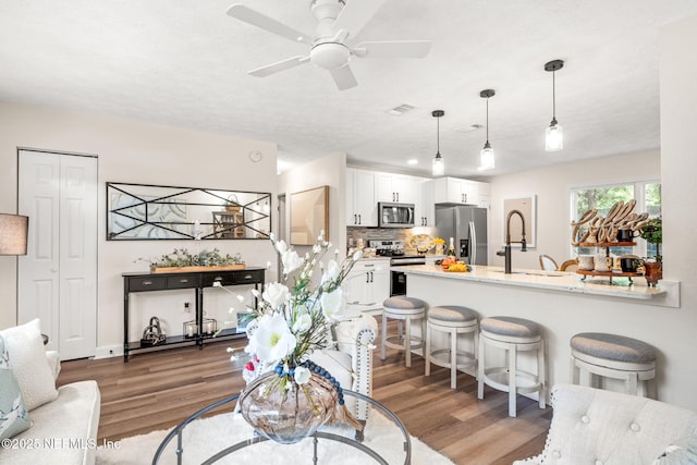 kitchen featuring a breakfast bar, a peninsula, stainless steel appliances, and wood finished floors