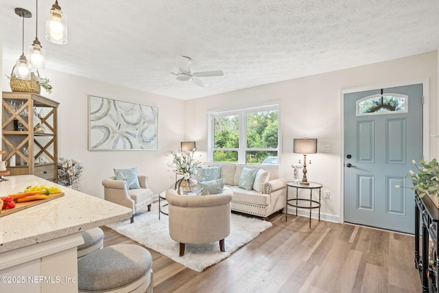 living area featuring a textured ceiling, wood finished floors, and a ceiling fan