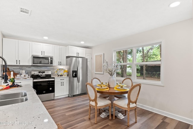 kitchen featuring decorative backsplash, appliances with stainless steel finishes, light wood-type flooring, and visible vents