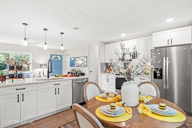 kitchen with visible vents, white cabinets, stainless steel appliances, and a sink