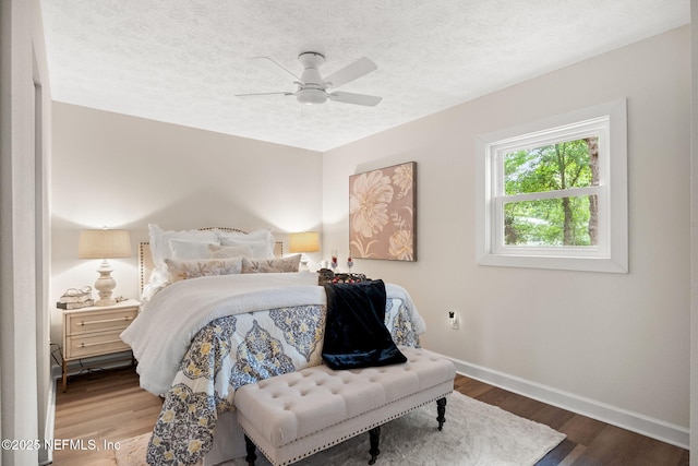 bedroom with baseboards, a textured ceiling, wood finished floors, and a ceiling fan