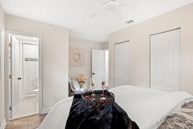 bedroom featuring visible vents, multiple closets, a ceiling fan, ensuite bathroom, and light wood finished floors