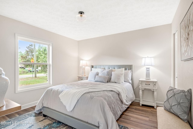 bedroom with wood finished floors, baseboards, and a textured ceiling