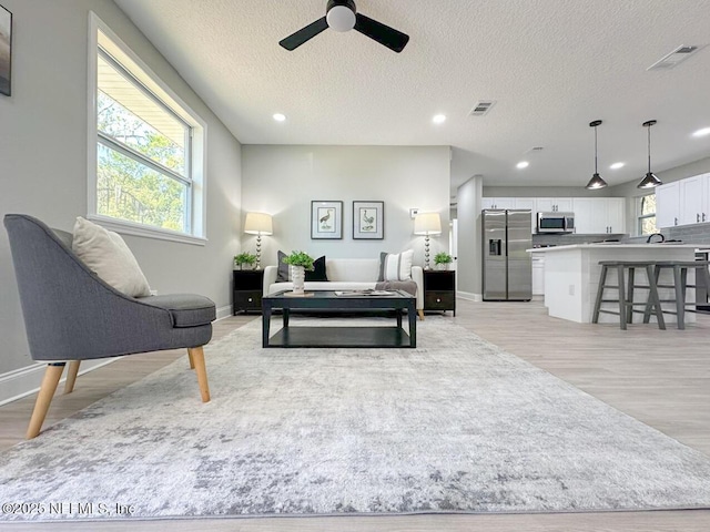 bedroom featuring light wood-type flooring, recessed lighting, visible vents, and stainless steel fridge with ice dispenser