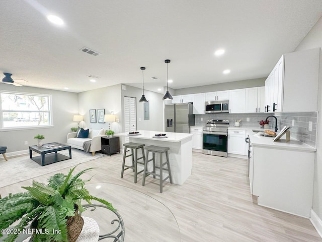 kitchen featuring stainless steel appliances, tasteful backsplash, visible vents, open floor plan, and a sink