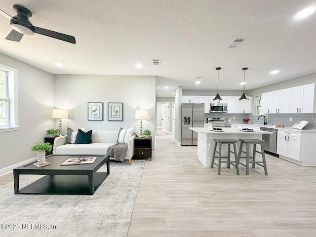 living room featuring visible vents, a ceiling fan, light wood-style flooring, and recessed lighting