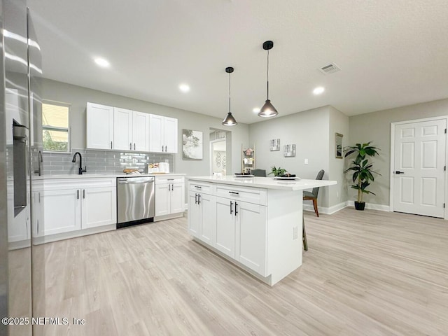 kitchen with dishwasher, light countertops, light wood-style flooring, and decorative backsplash