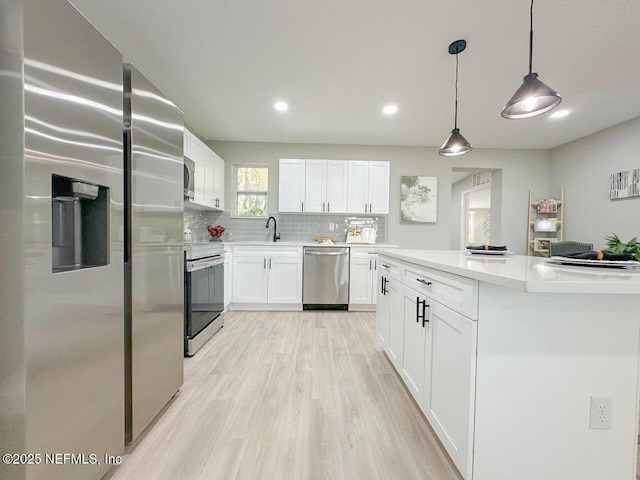 kitchen featuring stainless steel appliances, white cabinetry, light wood-style flooring, and tasteful backsplash