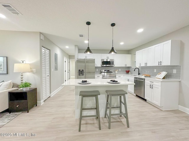 kitchen featuring appliances with stainless steel finishes, backsplash, a sink, and visible vents