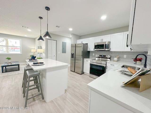 kitchen featuring stainless steel appliances, tasteful backsplash, light countertops, white cabinets, and a sink