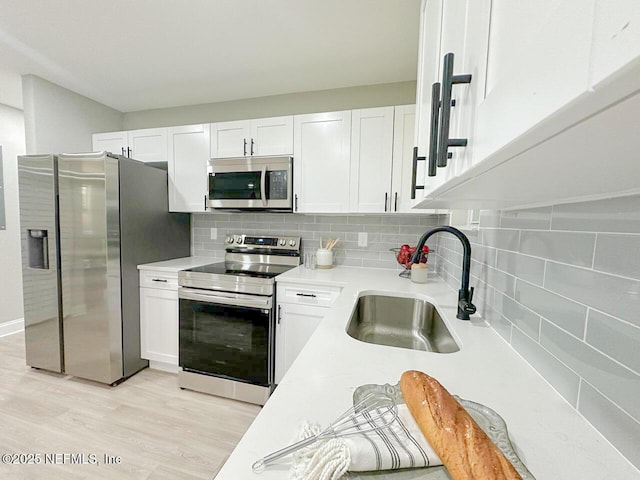 kitchen featuring a sink, white cabinetry, light countertops, appliances with stainless steel finishes, and decorative backsplash