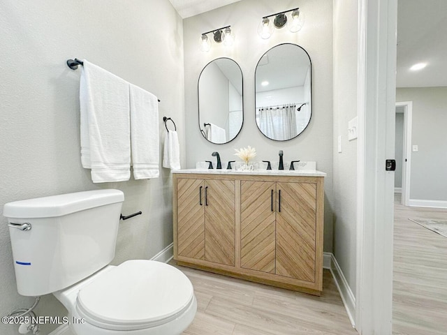 full bathroom featuring a sink, toilet, baseboards, and wood finished floors