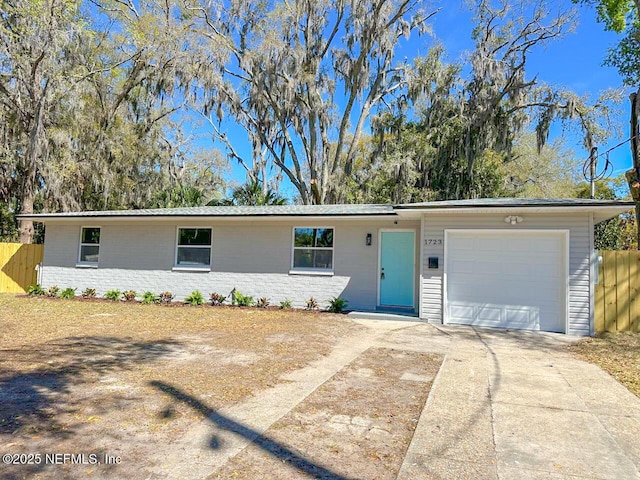 ranch-style home featuring concrete driveway, brick siding, fence, and an attached garage