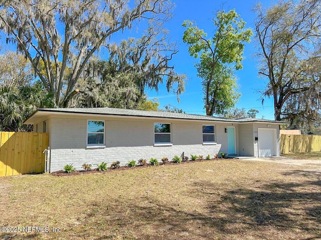 single story home featuring an attached garage, fence, concrete driveway, and brick siding