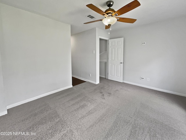 empty room with visible vents, carpet floors, baseboards, and a ceiling fan