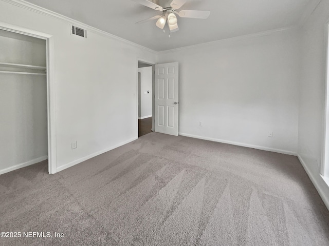 unfurnished bedroom featuring visible vents, crown molding, baseboards, carpet, and a closet