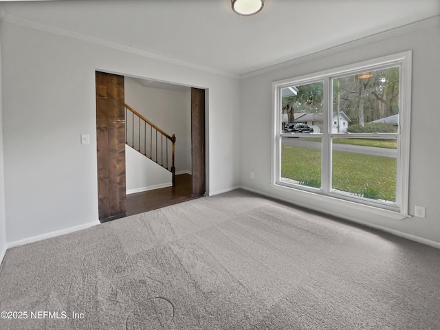 carpeted empty room featuring baseboards, ornamental molding, and stairs