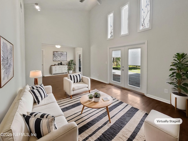 living area with french doors, baseboards, dark wood-style floors, and a towering ceiling