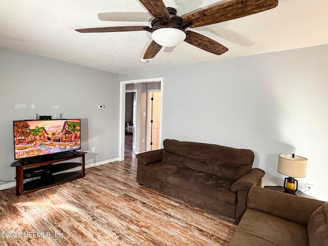 living room with a textured ceiling, wood finished floors, a ceiling fan, and baseboards