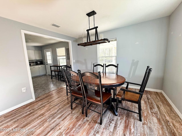 dining area featuring wood finished floors, visible vents, and baseboards