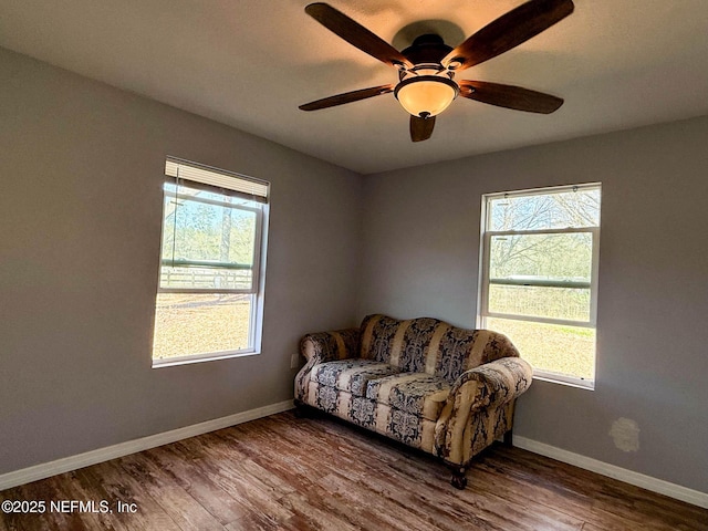 living area with ceiling fan, baseboards, and wood finished floors