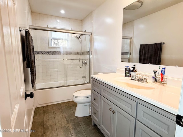 bathroom with wood tiled floor, combined bath / shower with glass door, vanity, and toilet