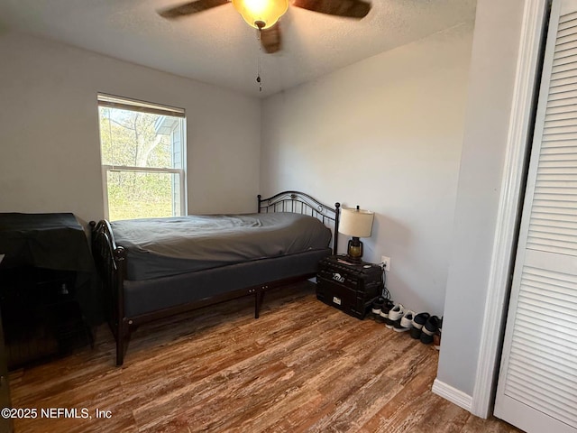 bedroom with ceiling fan, a textured ceiling, and wood finished floors