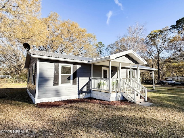 view of front facade with covered porch, metal roof, and a front yard