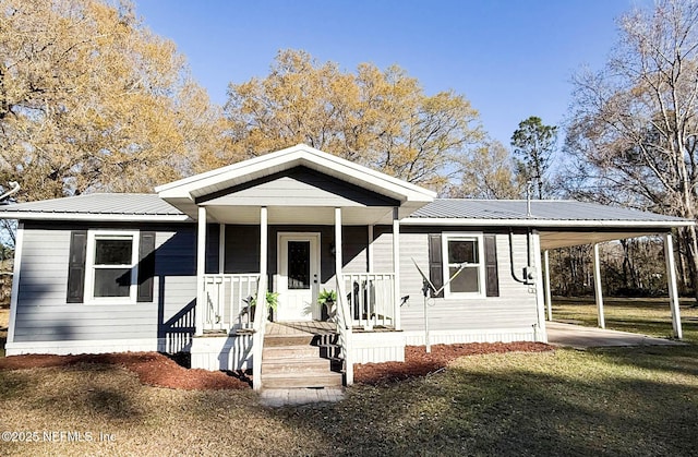 view of front facade featuring covered porch, metal roof, a carport, and a front yard