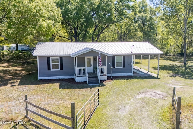 view of front of home featuring dirt driveway, metal roof, an attached carport, and a porch