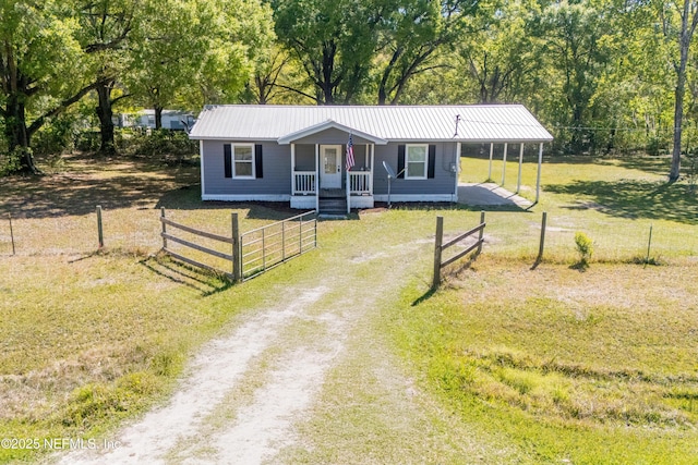 view of front facade featuring driveway, a front lawn, metal roof, a carport, and a fenced front yard